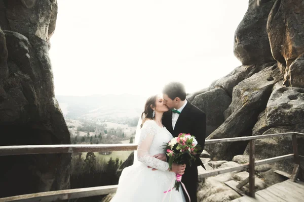 Boda pareja enamorada besándose y abrazándose cerca de rocas en hermoso paisaje —  Fotos de Stock