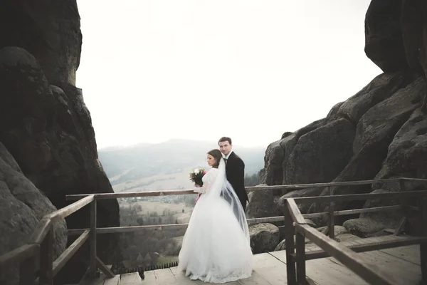 Свадебная пара влюблённая целуется и обнимается у скал на красивом ландшафте — стоковое фото
