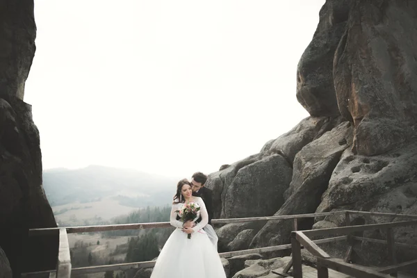 Happy bröllopsparet, bruden och brudgummen poserar nära klipporna med vacker utsikt — Stockfoto