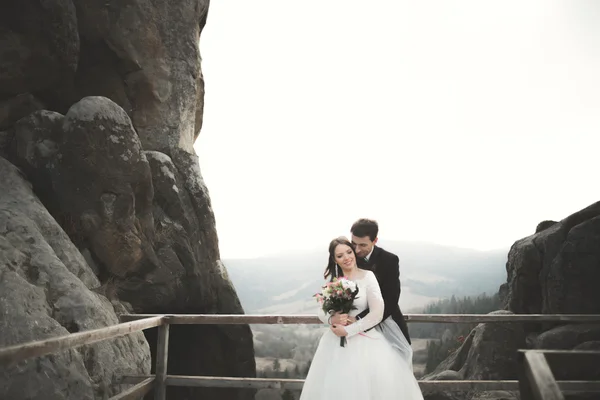 Casamento casal no amor beijando e abraçando perto de pedras na bela paisagem — Fotografia de Stock