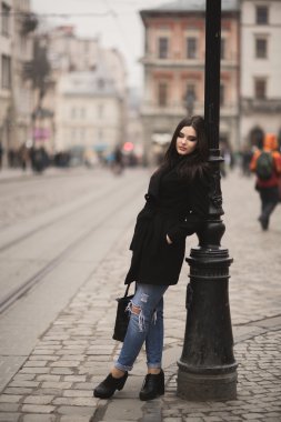 Güzel esmer genç kadın eski şehirde sokakta poz