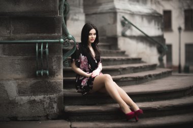 Güzel esmer genç kadın eski şehirde sokakta poz