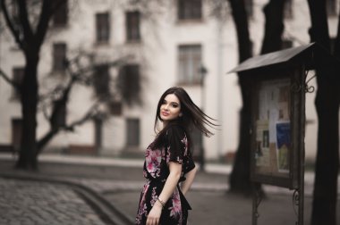 Güzel esmer genç kadın eski şehirde sokakta poz