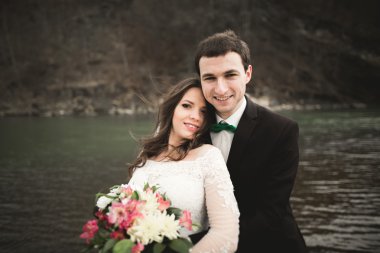 Öpüşme ve taşlarla Nehri yakınında kucaklayan güzel düğün çifti