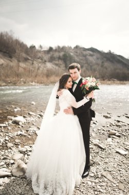 Mutlu evlilik çift, gelin ve damat zemin Dağları nın karşı temiz nehir poz
