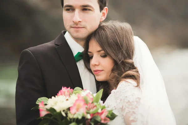 Casamento lindo casal beijando e abraçando perto do rio com pedras — Fotografia de Stock