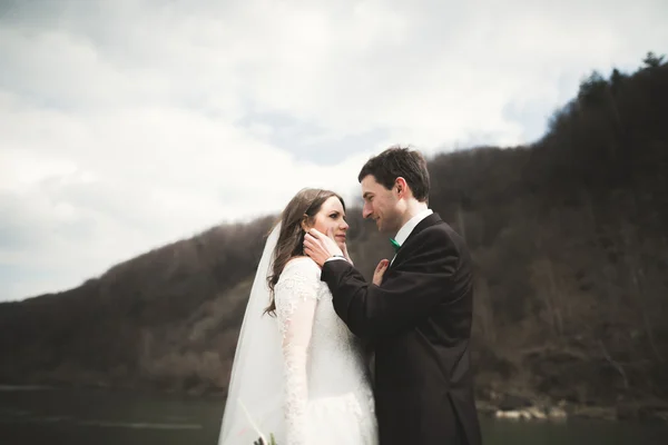 Щаслива весільна пара, наречена і наречений позує акуратну річку на тлі гір — стокове фото