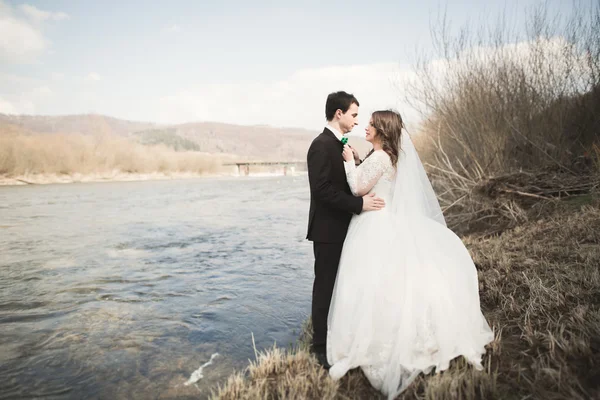 Joyeux jeunes mariés, mariés posant sur la rivière avec de belles vues — Photo
