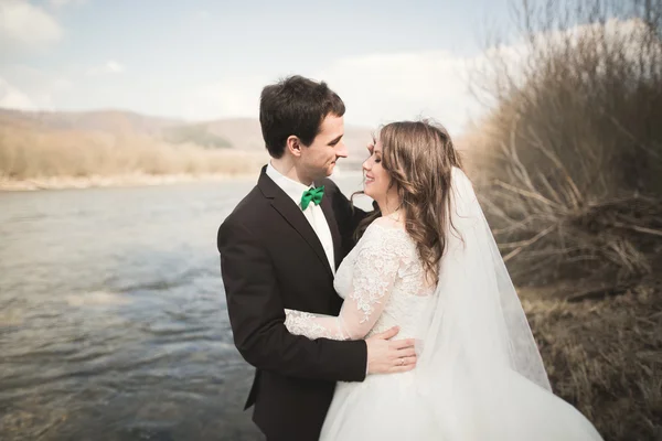 Ευτυχισμένος νεόνυμφους, νύφη και ο γαμπρός που παρουσιάζουν στον ποταμό με όμορφη θέα — Φωτογραφία Αρχείου