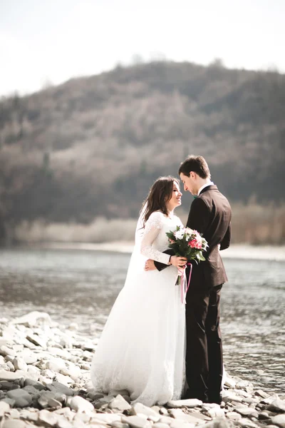 Joyeux jeunes mariés, mariés posant sur la rivière avec de belles vues — Photo