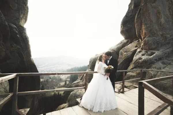 Boda pareja enamorada besándose y abrazándose cerca de rocas en hermoso paisaje —  Fotos de Stock