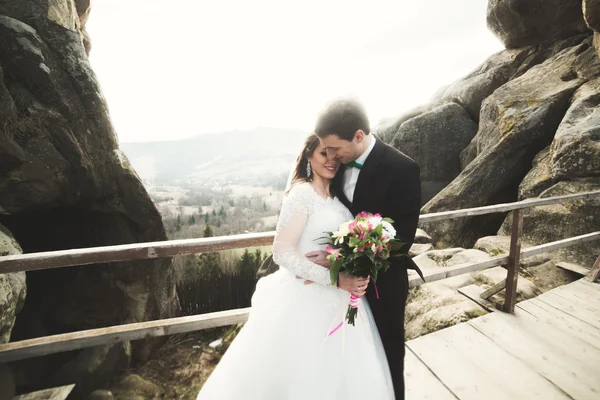 Щаслива весільна пара, наречена і наречений позують біля скель з красивими видами — стокове фото
