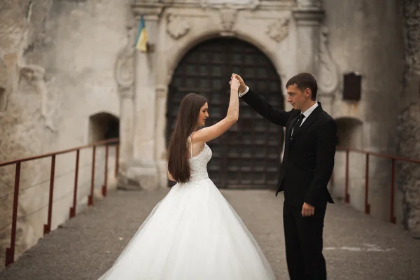 Feliz boda pareja abrazándose y sonriendo el uno al otro en el fondo hermosas plantas en el castillo — Foto de Stock