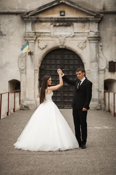 Feliz boda pareja abrazándose y sonriendo el uno al otro en el fondo hermosas plantas en el castillo — Foto de Stock