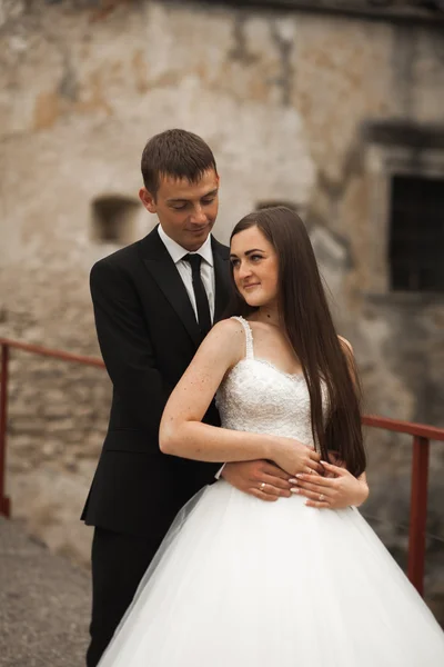 Feliz boda pareja abrazándose y sonriendo el uno al otro en el fondo hermosas plantas en el castillo — Foto de Stock