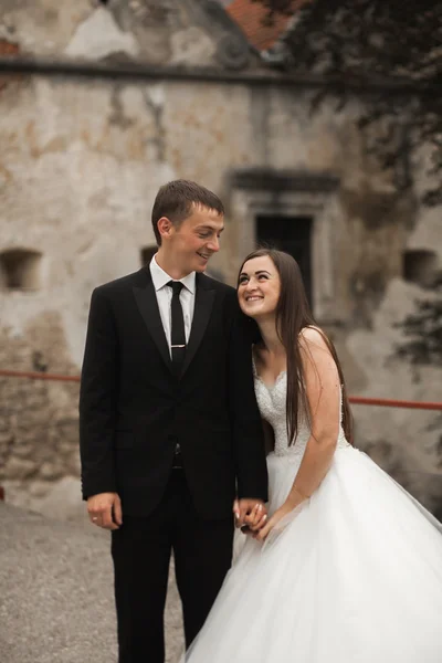 Feliz boda pareja abrazándose y sonriendo el uno al otro en el fondo hermosas plantas en el castillo — Foto de Stock