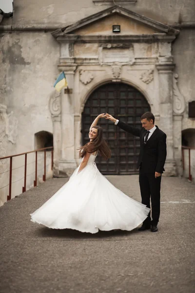 Feliz boda pareja abrazándose y sonriendo el uno al otro en el fondo hermosas plantas en el castillo — Foto de Stock