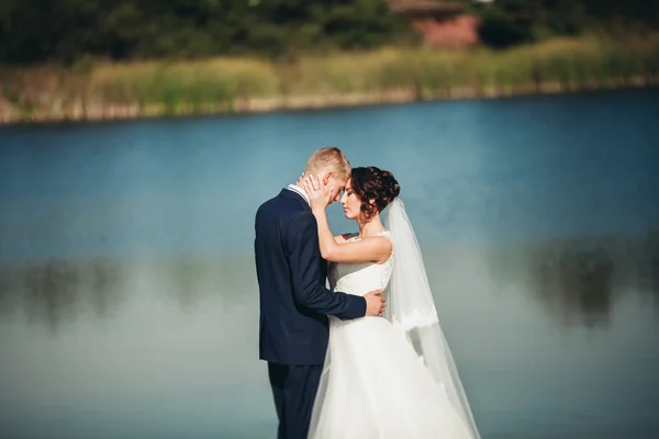 El amor y la pasión - el beso de la pareja casada joven de boda cerca del lago — Foto de Stock