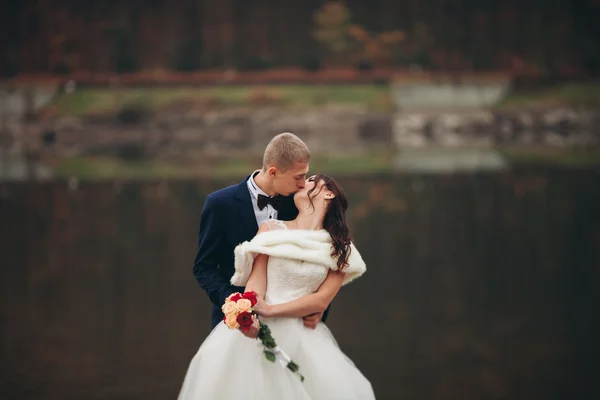 Amore e passione - bacio di coppia nuziale giovane sposata vicino a lago — Foto Stock