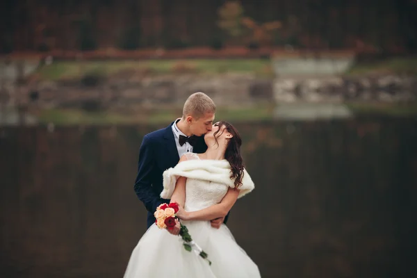 El amor y la pasión - el beso de la pareja casada joven de boda cerca del lago —  Fotos de Stock