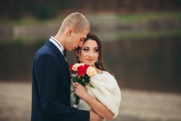 El amor y la pasión - el beso de la pareja casada joven de boda cerca del lago — Foto de Stock