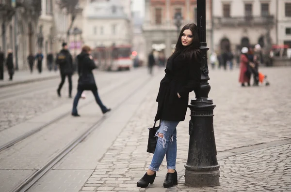 Krásná brunetka mladá žena pózuje na ulici ve starém městě — Stock fotografie