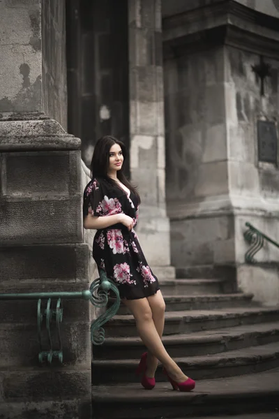 Güzel esmer genç kadın eski şehirde sokakta poz