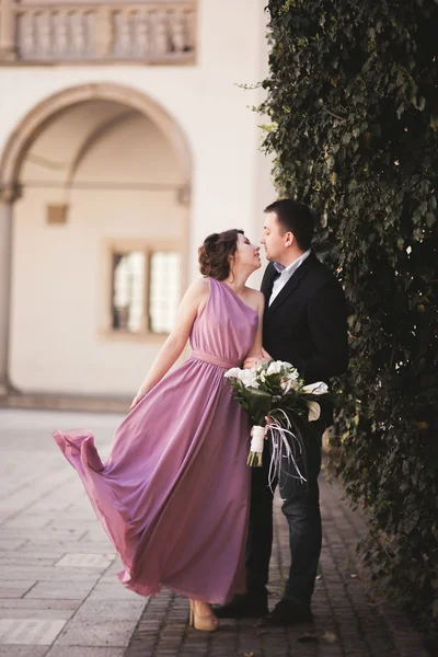 Feliz pareja de boda, novio, novia con vestido rosa abrazándose y sonriendo entre sí en las paredes de fondo en el castillo —  Fotos de Stock