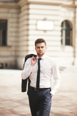 Yakışıklı, şık, genç bir iş adamı. Açık havada portre pozu veriyor.