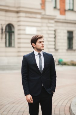 Yakışıklı, şık, genç bir iş adamı. Açık havada portre pozu veriyor.
