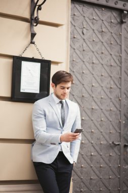 Yakışıklı, şık, genç bir iş adamı. Açık havada portre pozu veriyor.