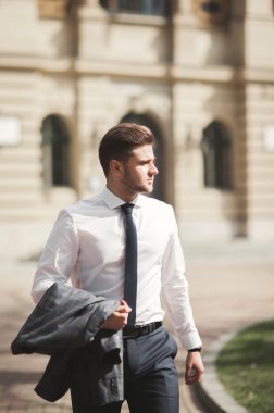 Yakışıklı, şık, genç bir iş adamı. Açık havada portre pozu veriyor.