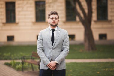 Yakışıklı, şık, genç bir iş adamı. Açık havada portre pozu veriyor.