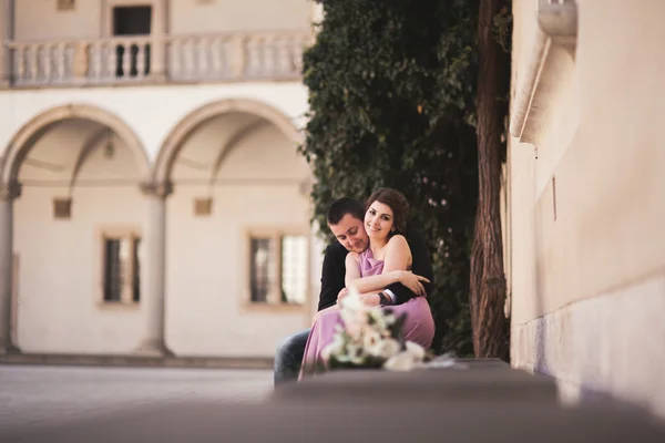 Happy wedding couple, groom, bride with pink dress hugging and smiling each other on the background walls in castle — Stock Photo, Image