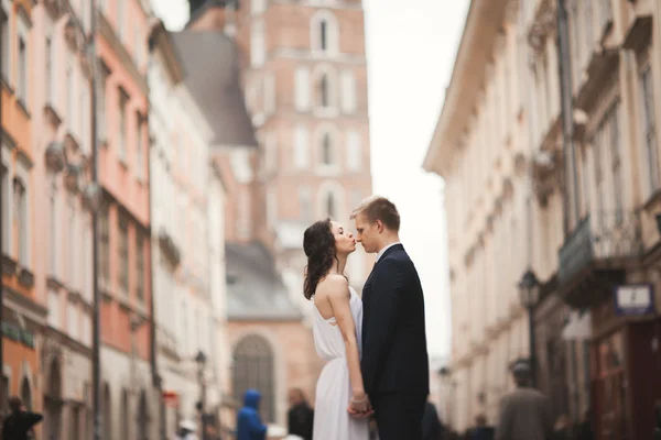 Hermosa pareja de boda, novia, novio besándose y abrazándose de pie en la multitud —  Fotos de Stock