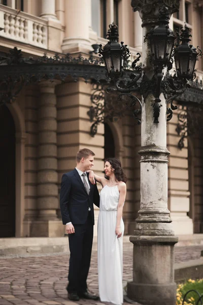 Schönes Hochzeitspaar, Braut, Bräutigam küsst und umarmt sich vor dem Hintergrund des Theaters — Stockfoto