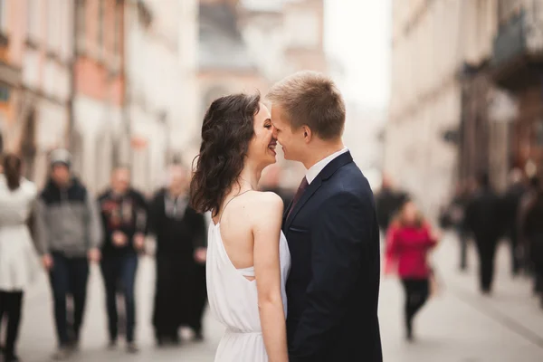 Nádherná svatební pár, nevěsta, ženich, líbání a objímání stojí v davu — Stock fotografie