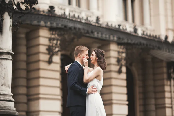 Hermosa pareja de boda, novia, novio besándose y abrazándose contra el fondo del teatro —  Fotos de Stock