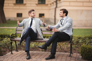 Konuşma ve açık havada gülümseyen iki şık iş adamları