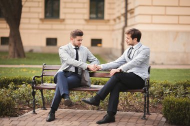 Takım elbiseli el sıkışan iki şık iş adamları