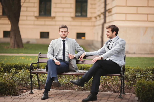 Dos hombres de negocios elegantes hablando y sonriendo al aire libre —  Fotos de Stock