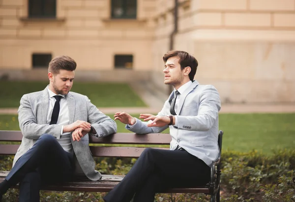 Dois empresários elegantes falando e sorrindo ao ar livre — Fotografia de Stock