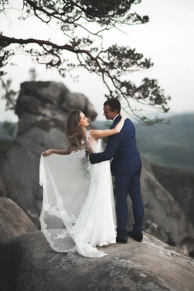 Hermosa pareja de boda besándose y abrazándose cerca de los acantilados con impresionantes vistas —  Fotos de Stock