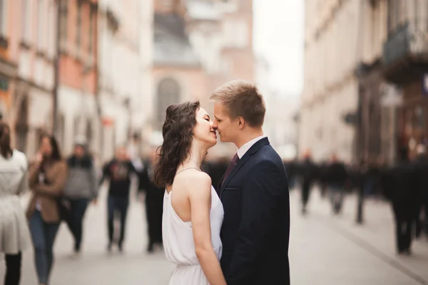 Gorgeous wedding couple, bride, groom kissing and hugging standing in the crowd — Stock Photo, Image