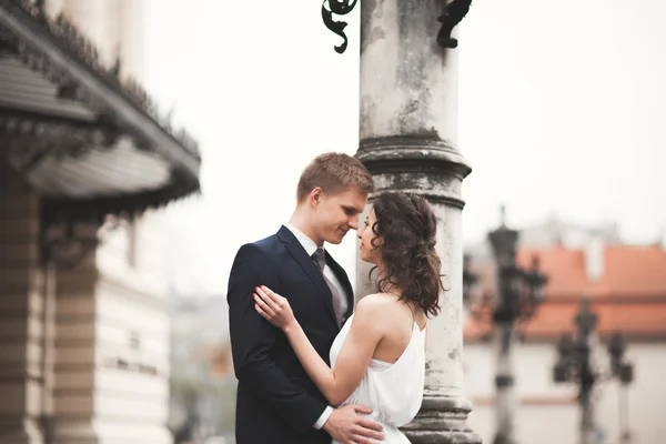 Красивая свадебная пара, невеста, жених целуется и обнимается на фоне театра — стоковое фото