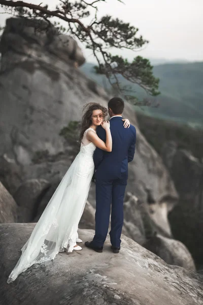 Gorgeous wedding couple kissing and hugging near the cliffs with stunning views — Stock Photo, Image