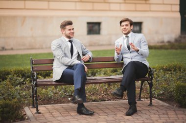 Konuşma ve açık havada gülümseyen iki şık iş adamları