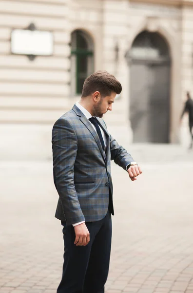 Hombre de negocios confiado mirando su reloj de pulsera en traje —  Fotos de Stock