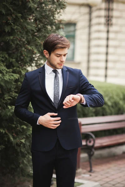 Hombre de negocios confiado mirando su reloj de pulsera en traje —  Fotos de Stock