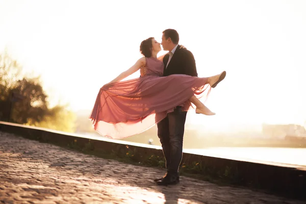 Casamento casal, noivo e vestido posando perto do rio com um copo ao pôr do sol — Fotografia de Stock